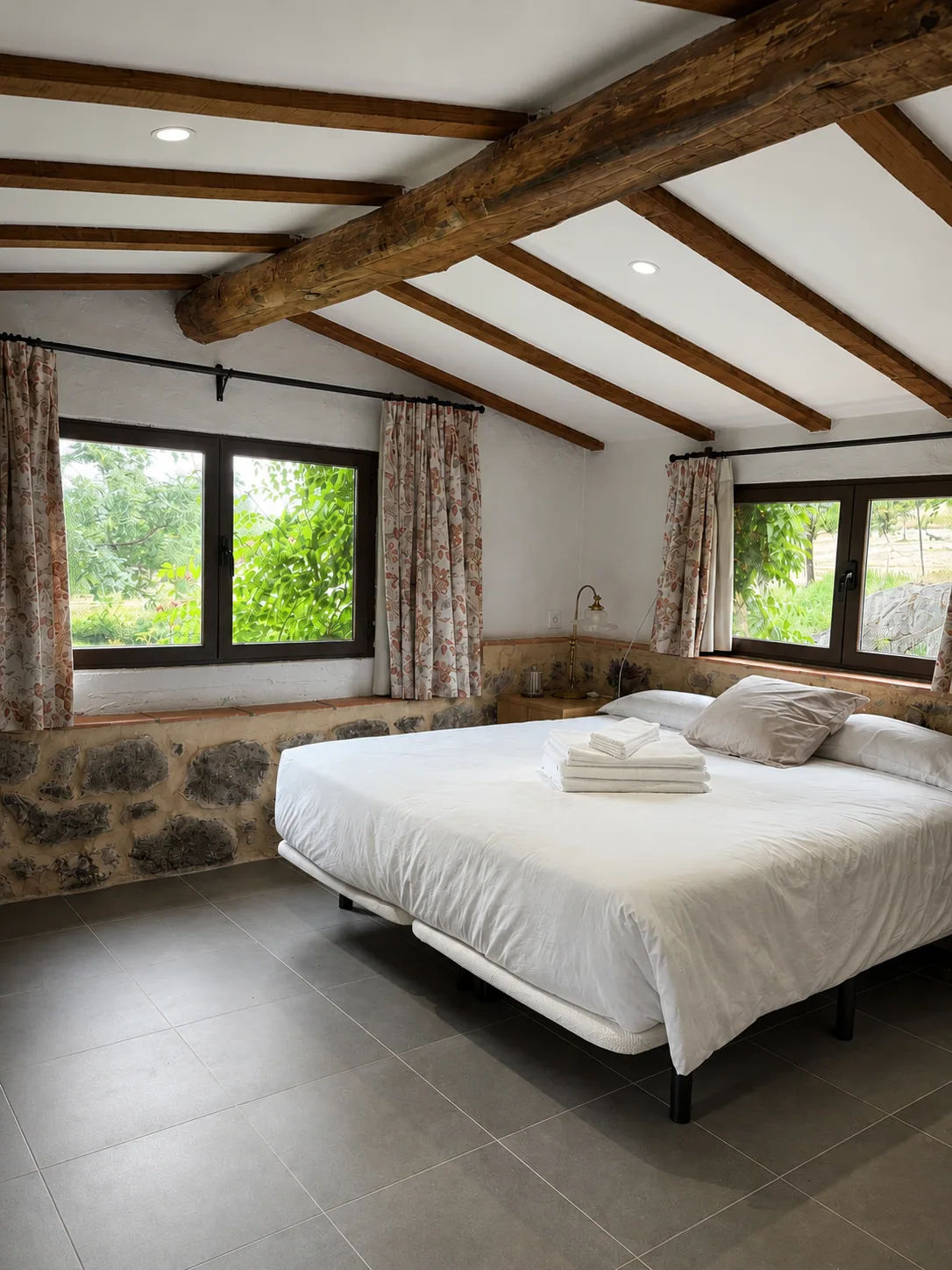 Bedroom of Villa Alardos with a stone wall and windows onto the countryside