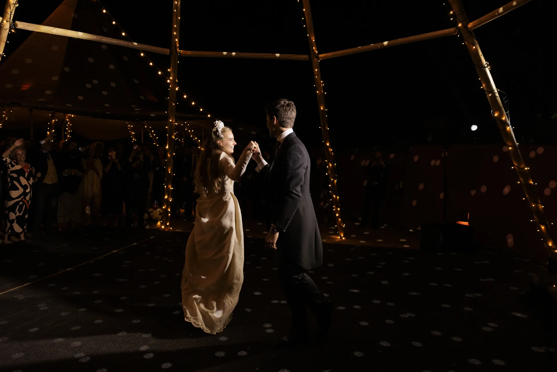 The couple dance under the string lights
