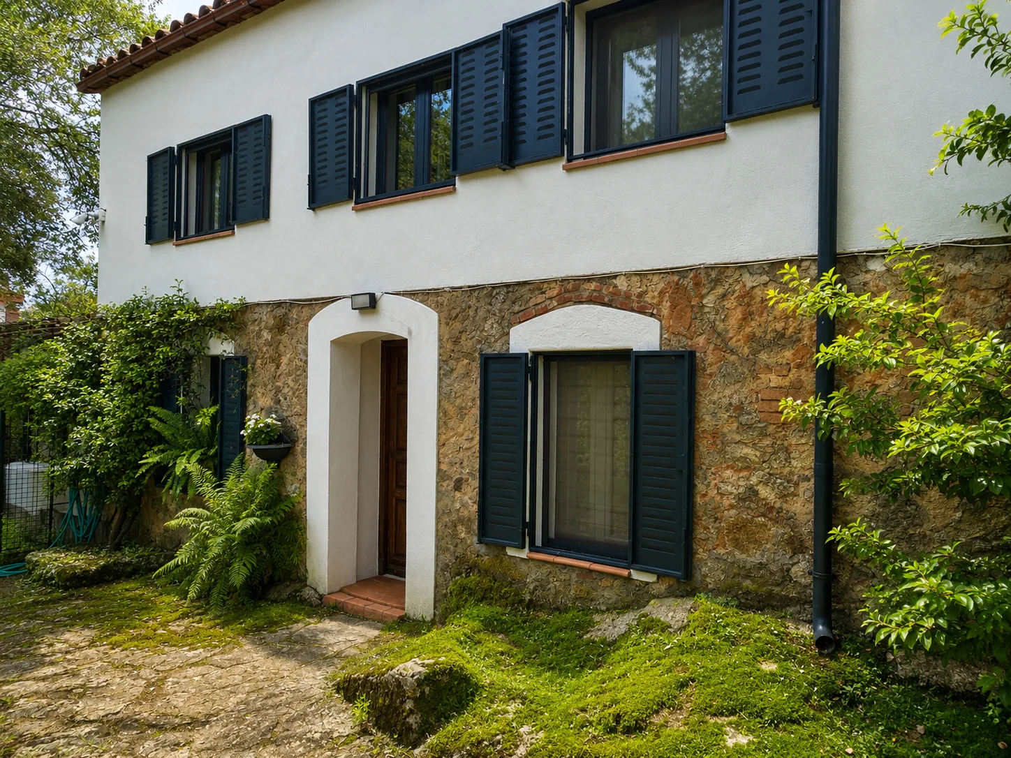 Stone entrance of Villa Alardos among the greenery