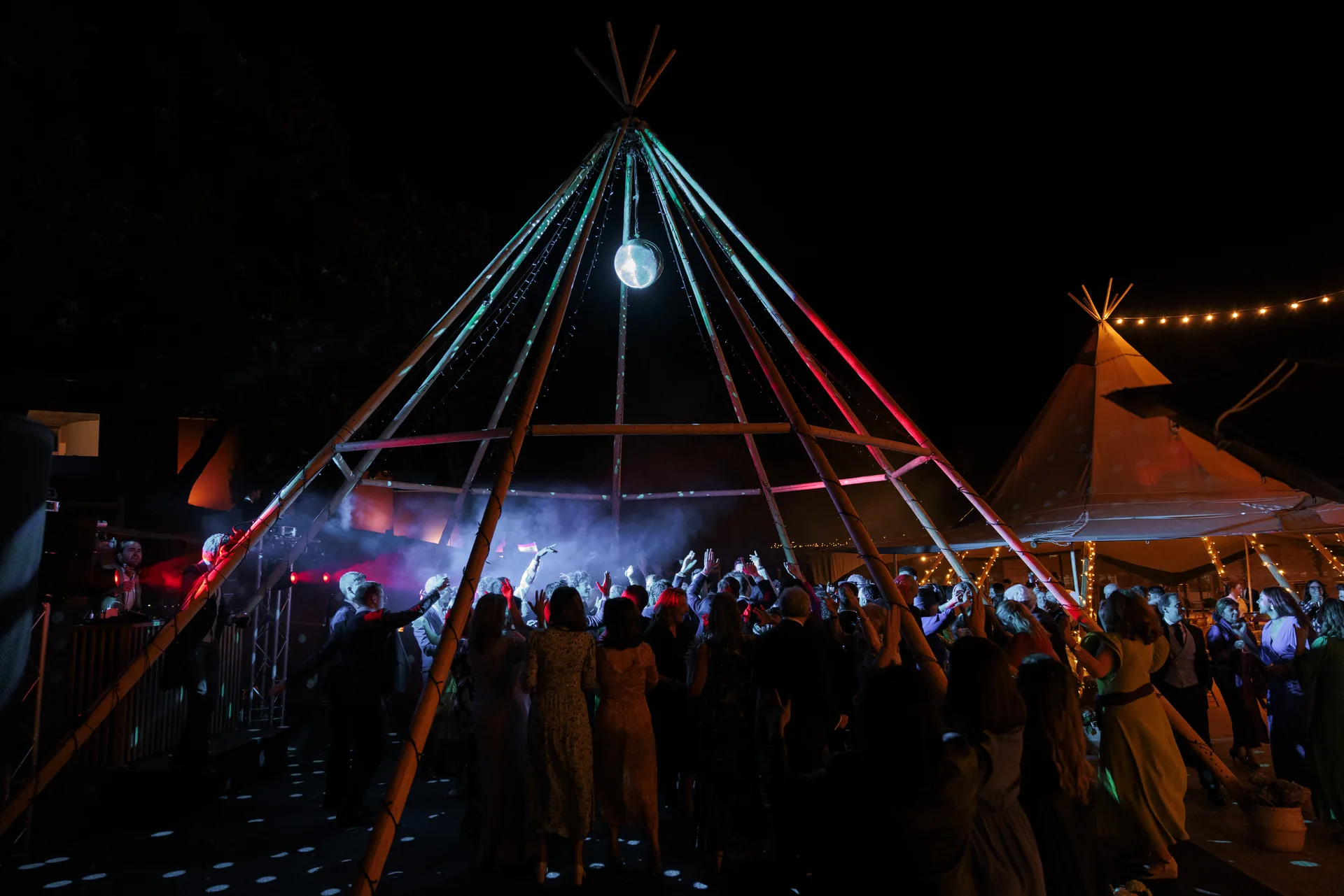 Guests dancing under the illuminated party structure