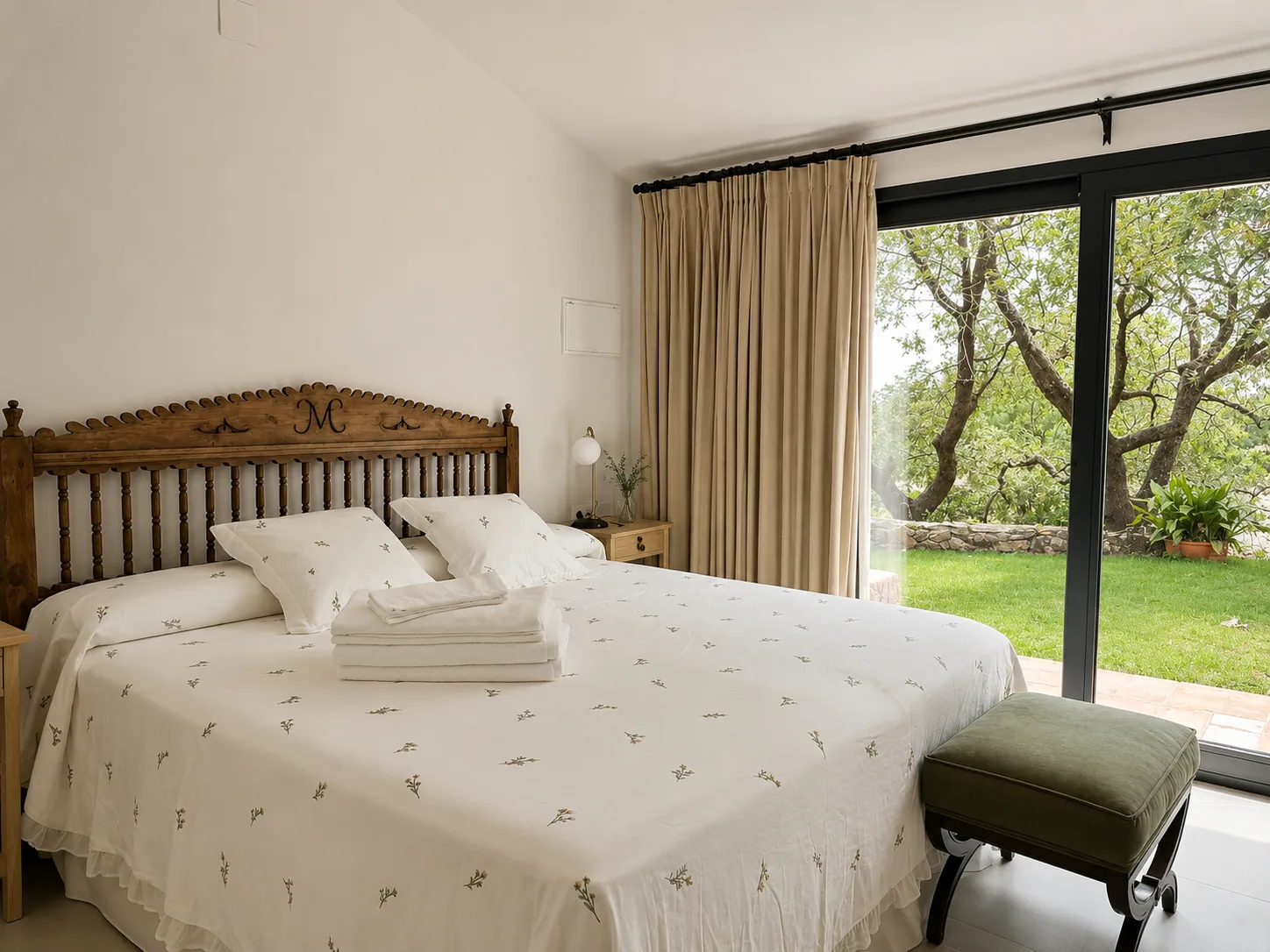 Bedroom of Villa Alardos with a carved wooden headboard and window onto the garden