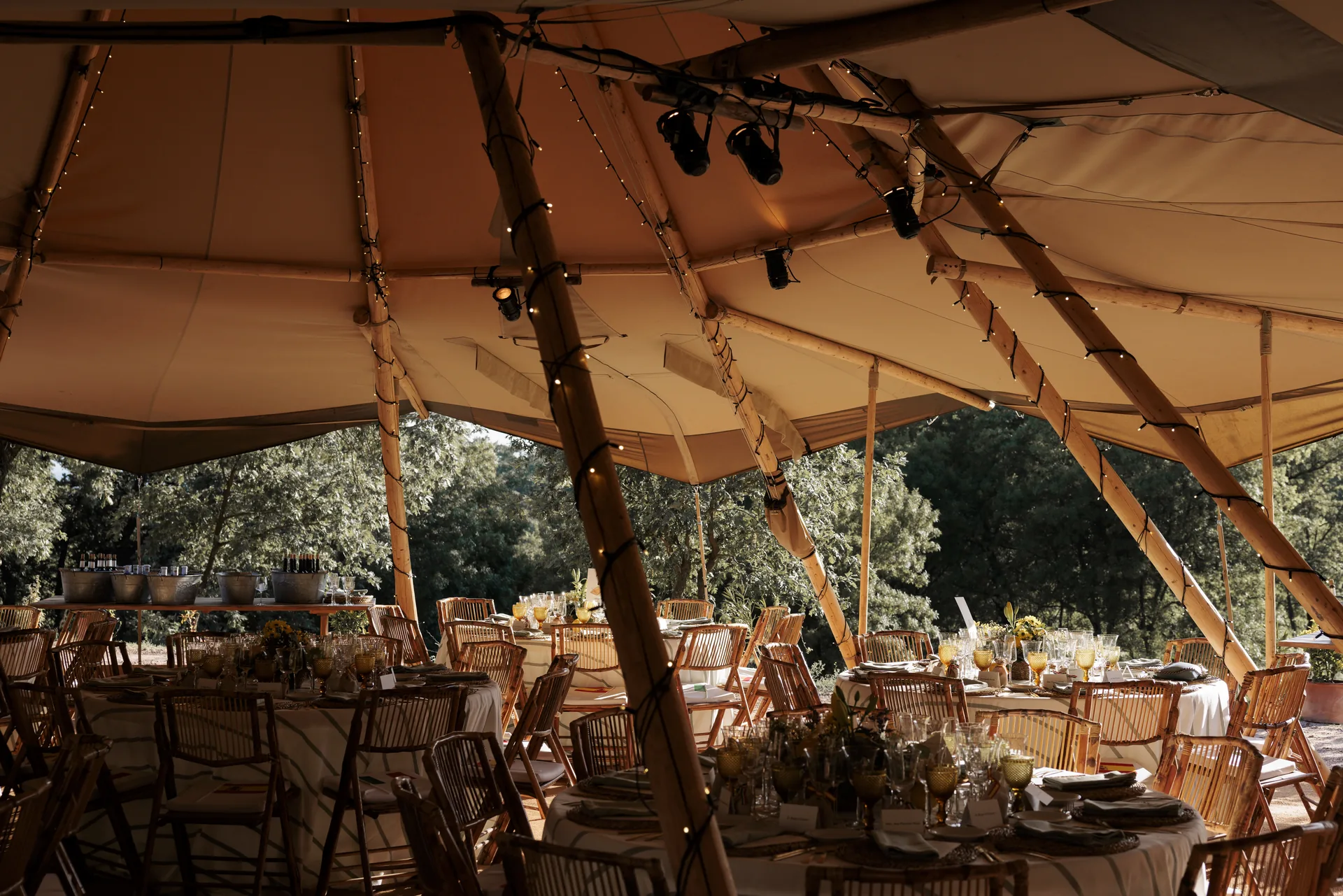 Dressed wedding tables under the marquee open to the holm oak grove