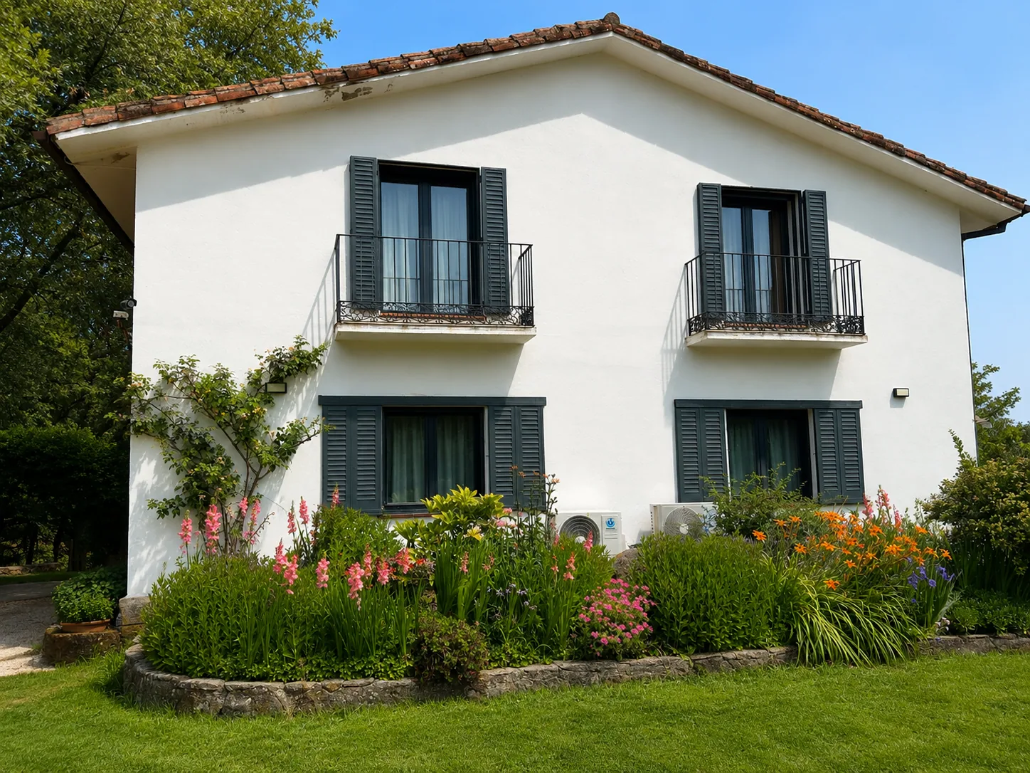 White facade of Villa Alardos with balconies and a flowering border