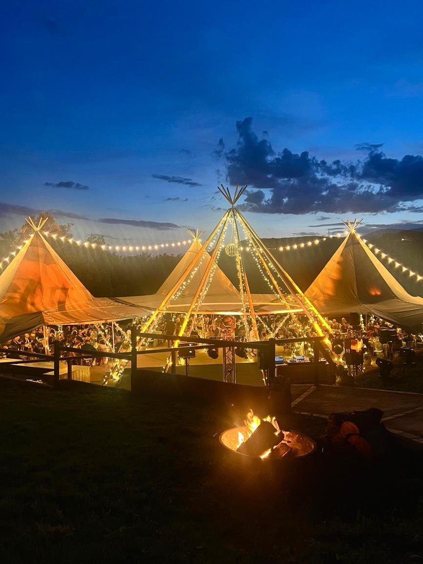 Illuminated marquee and an open fire during a night on the estate
